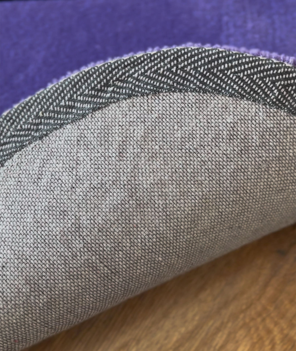Woven non slip backing on the purple rug, close up of the bound edge and base fabric