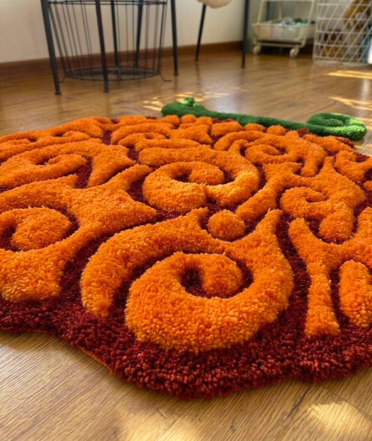 Hand tufted swirl fruit area rug, raised orange curls over a dark red base, close up pile detail