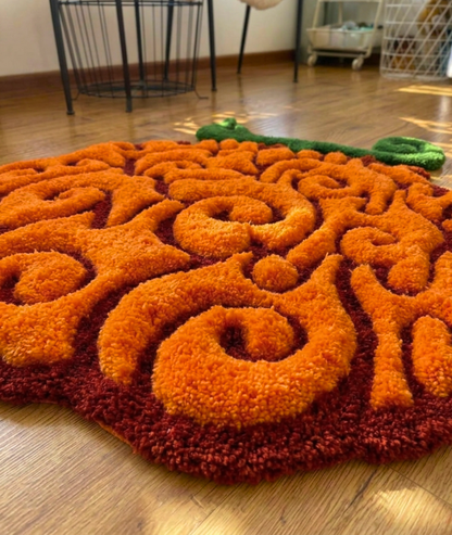 Hand tufted swirl fruit area rug, raised orange curls over a dark red base, close up pile detail