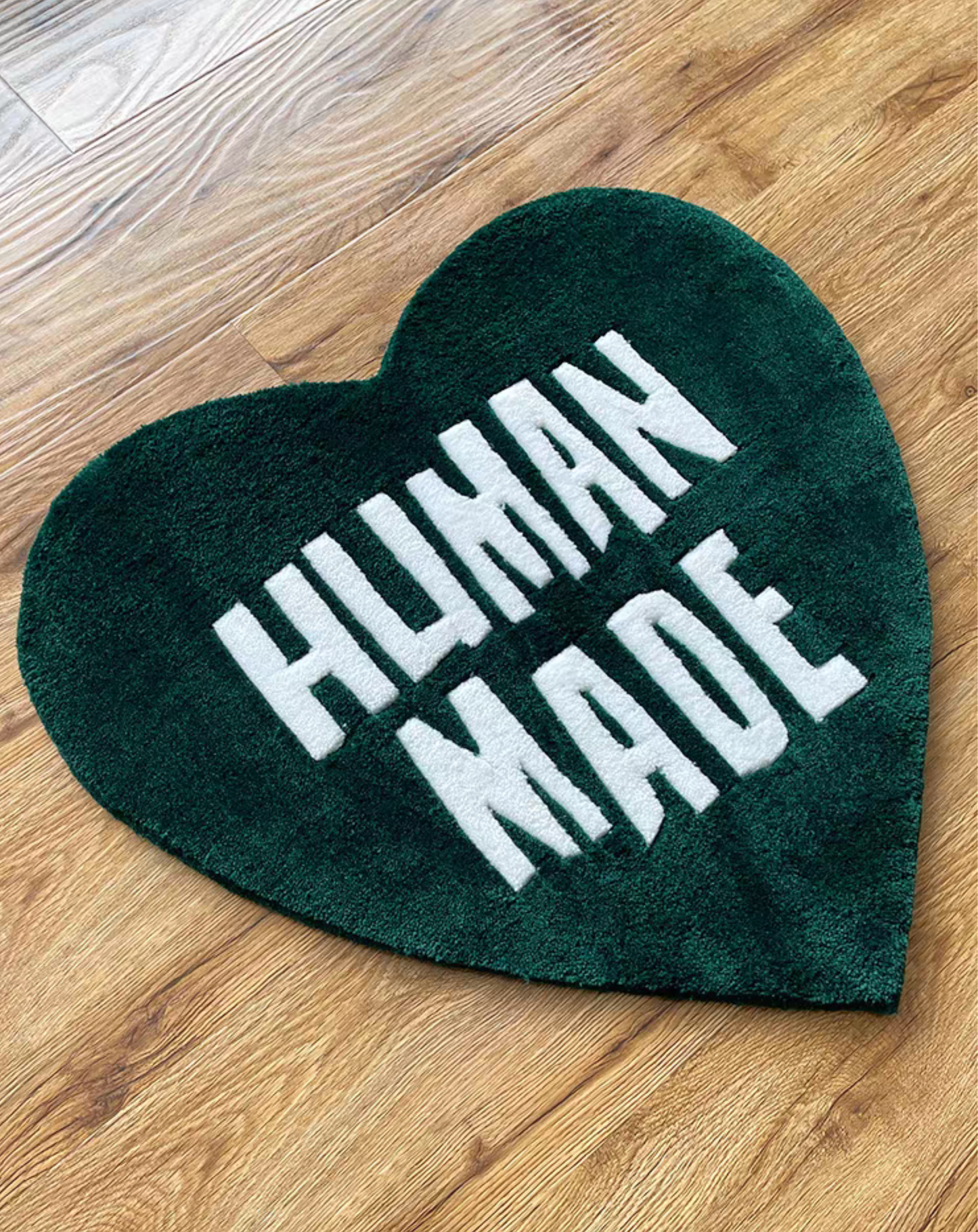 Human Made green heart rug on wooden floor in bedroom. Handmade green white tufted heart carpet. Sneakerhead hypebeast streetwear room floor decor.