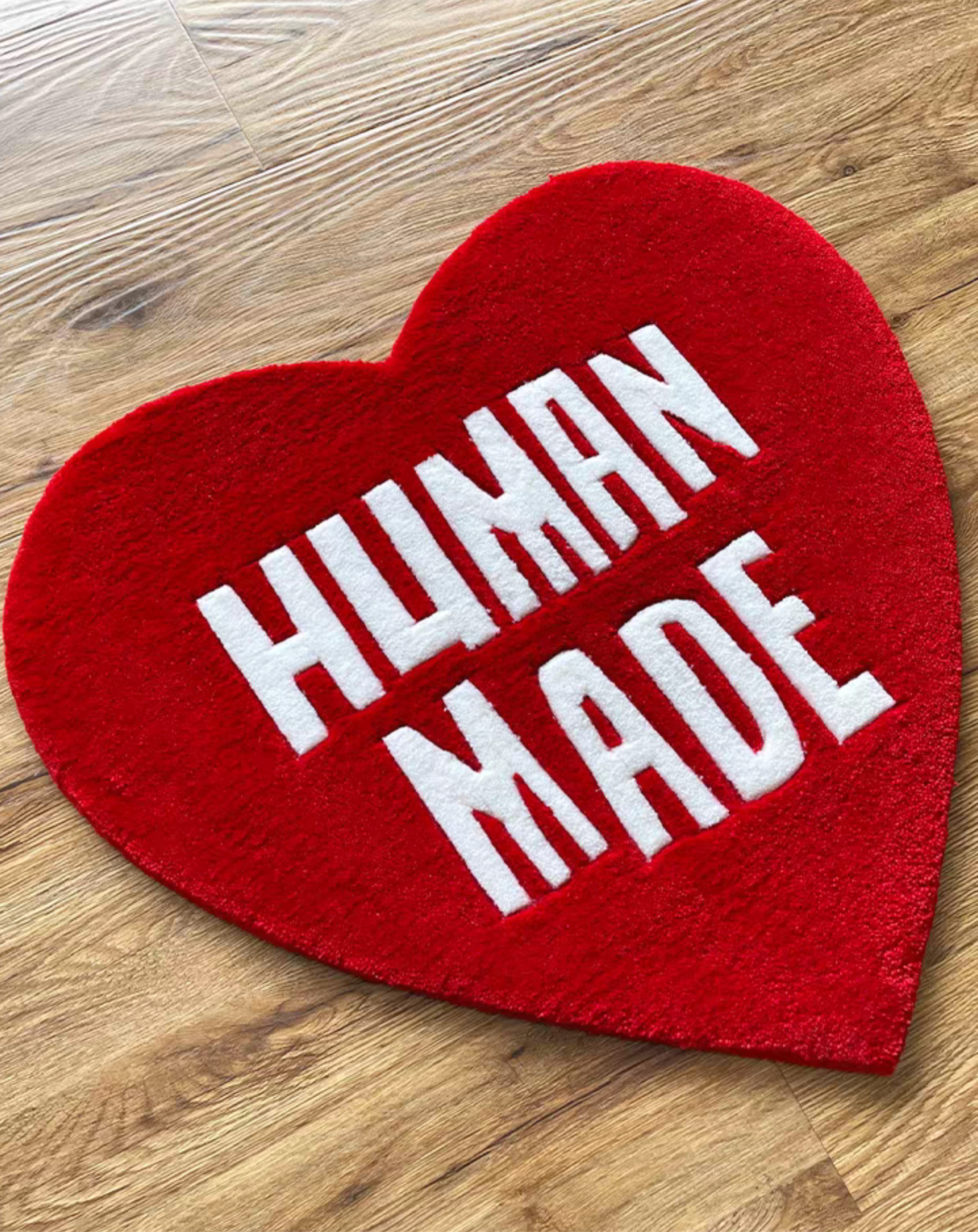Hypebeast Human Made red white heart rug laying on floor. Hand-tufted red heart carpet in sneaker room. Streetwear bedroom gaming setup room decor.