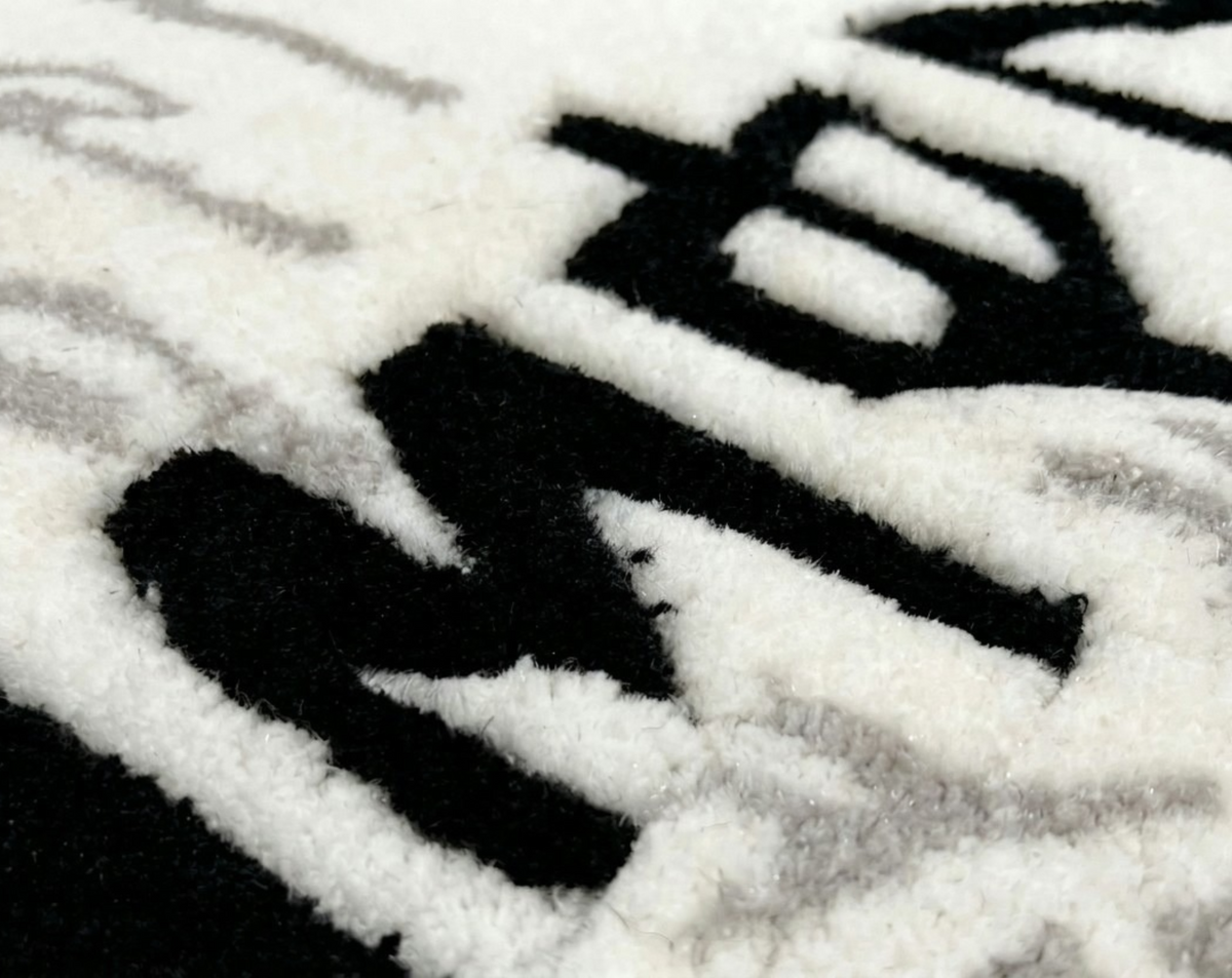 White Monster Rug extreme close up of black lettering in thick high density tufted acrylic pile