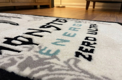 Gaming room rug close up of Energy and Zero Ultra lettering in black and blue on soft white acrylic yarn
