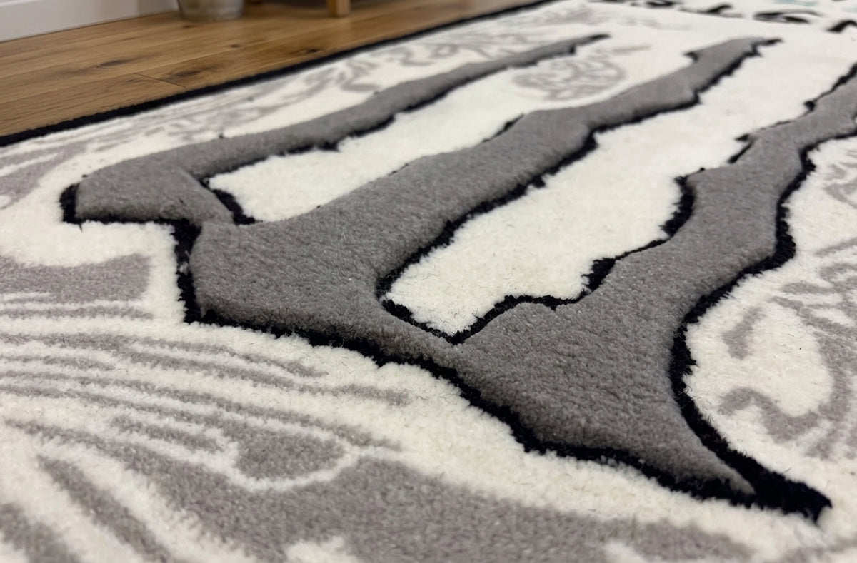 Hand tufted can shaped rug detail of the grey claw mark pattern with black outline and thick pile texture