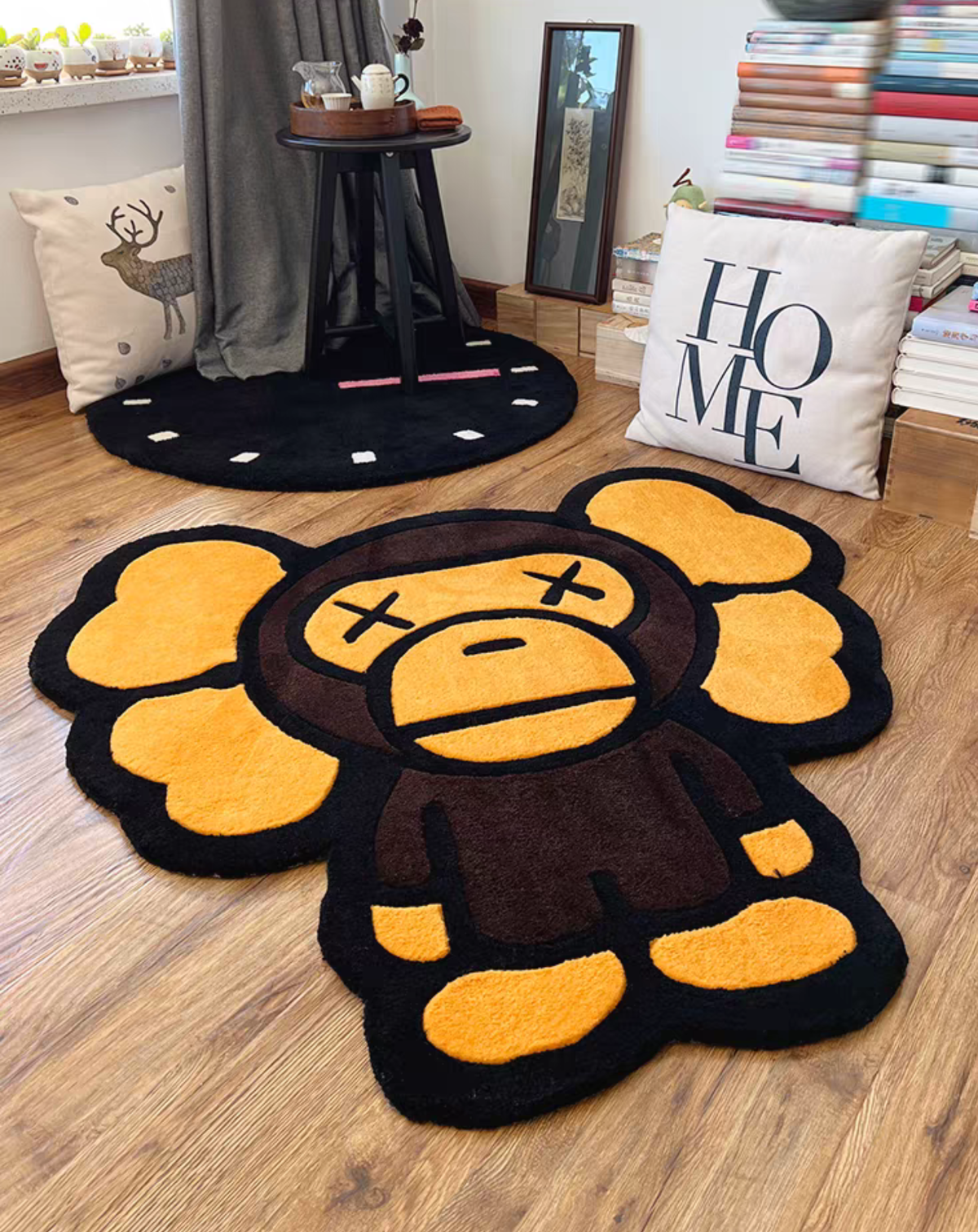 Kaws Bape Milo Character Rug Floor Placement, styled on a light wood floor in a cozy room setting with a clock rug and decorative pillows in the background.