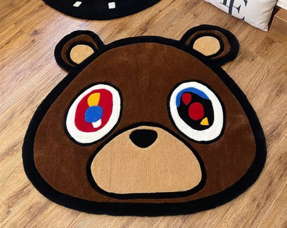 Kanye Dropout Bear shaped area rug with colorful abstract eyes, placed on a light brown wooden floor.