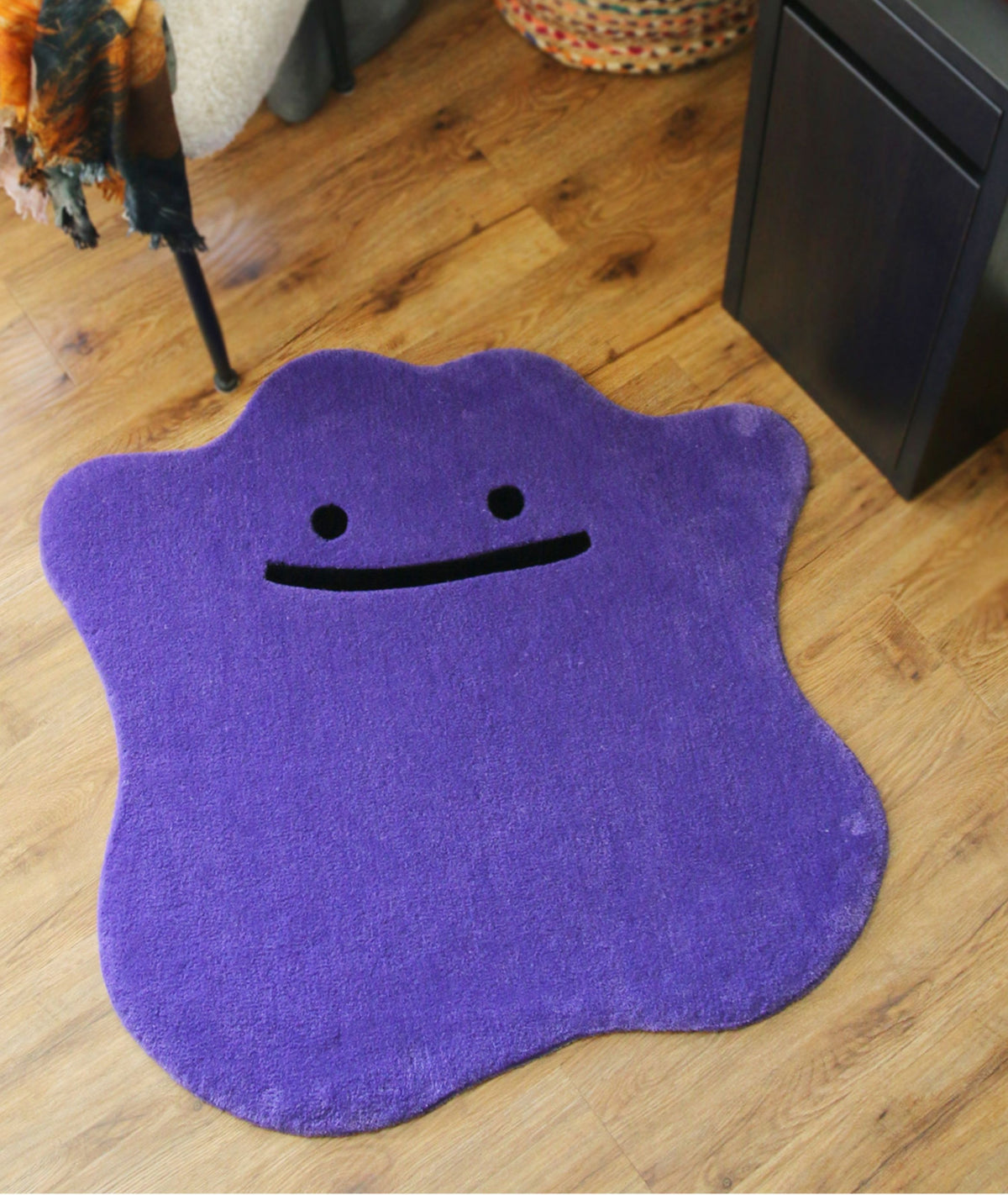 Purple blob rug with a smiling face on a wood floor, hand tufted cute room decor, full top view