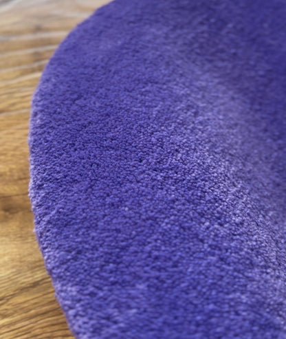 Macro shot of purple rug pile, dense looped acrylic yarn texture on a wood floor
