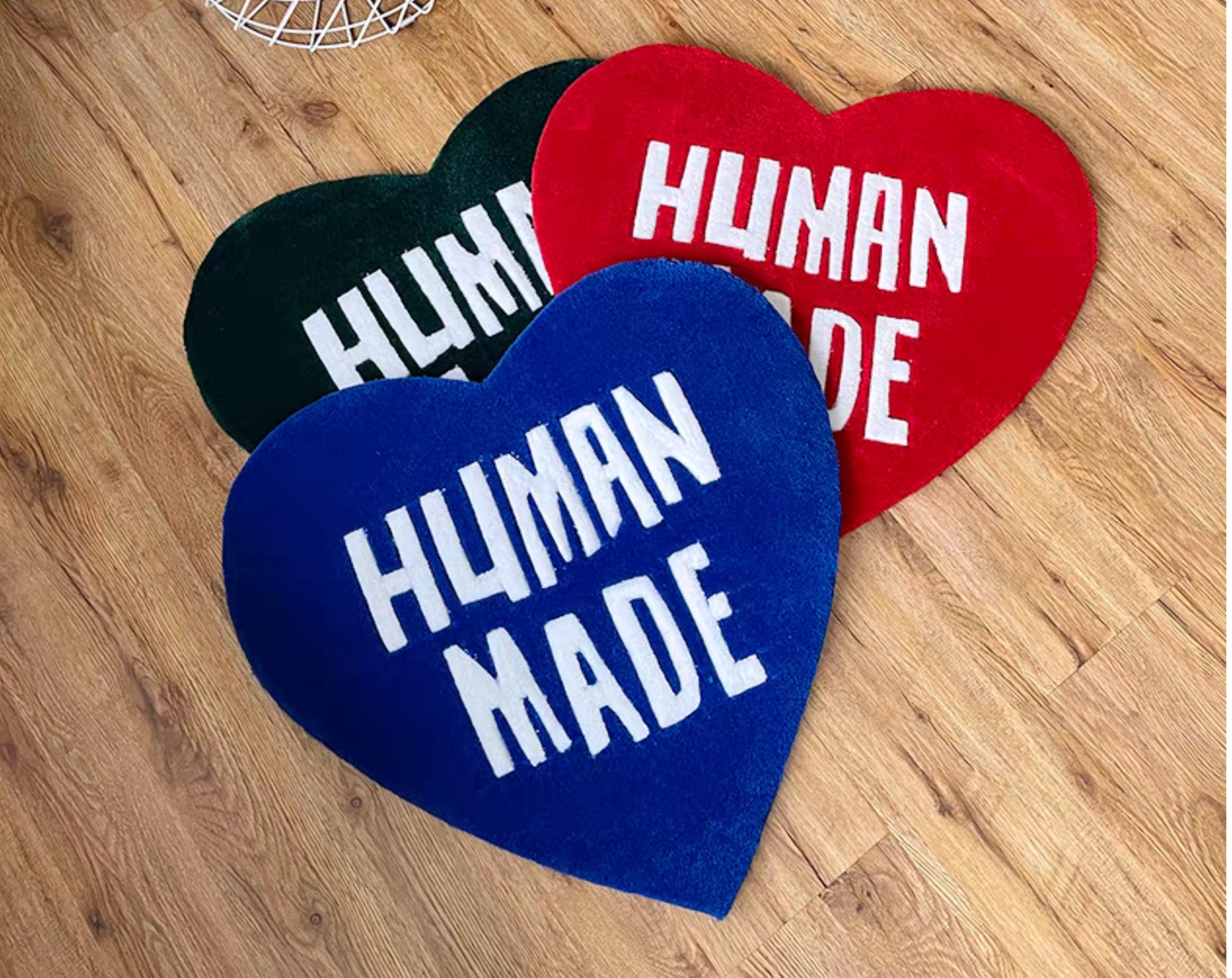 Hypebeast Human Made heart rug set green red blue laying on floor. Hand-tufted heart carpets in sneaker room. Streetwear bedroom gaming setup room decor collection.