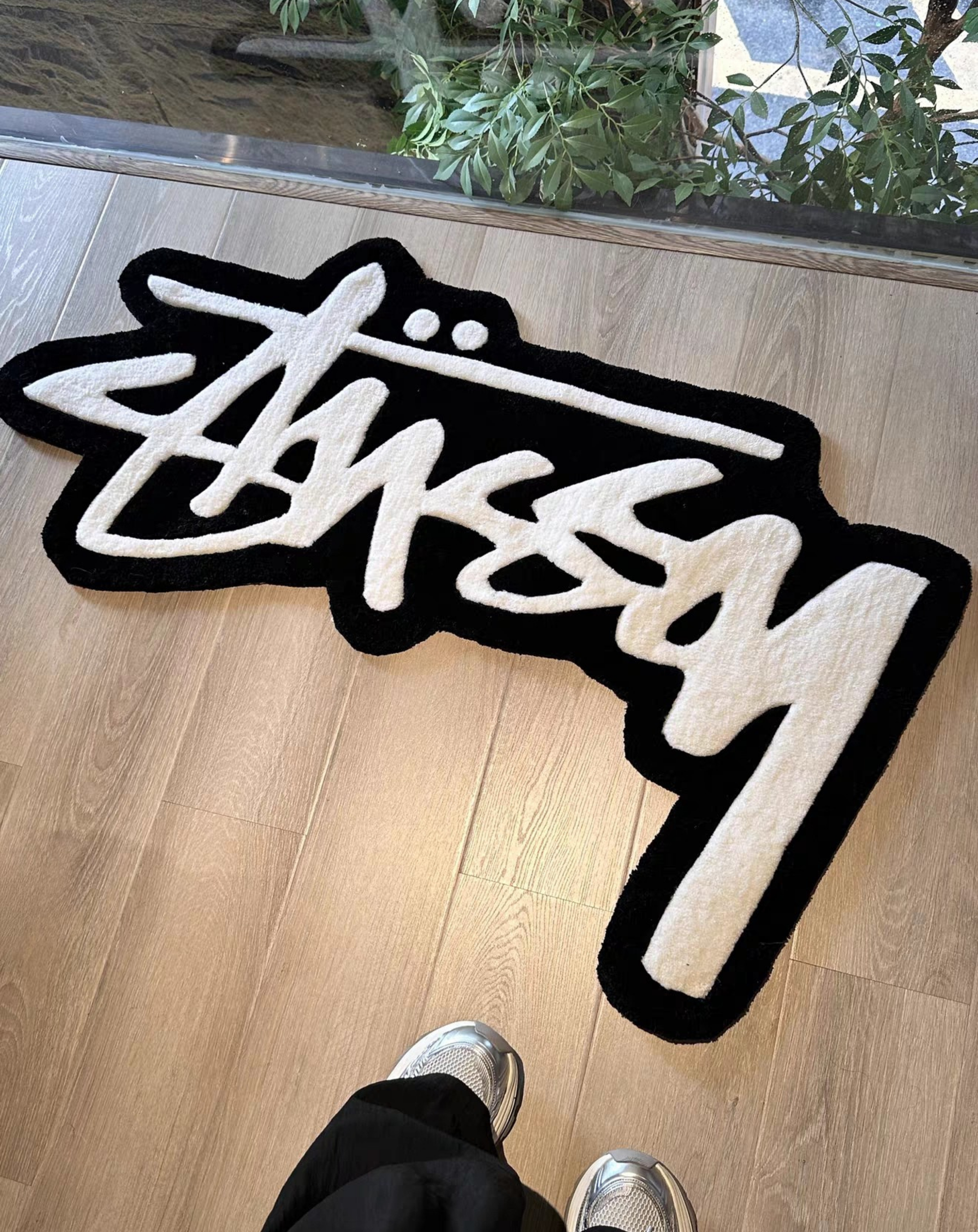 Graffiti logo shaped tufted rug black cream white thick pile close up texture, streetwear inspired bedroom floor rug for hypebeast and sneaker collectors