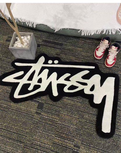 Streetwear script rug placed beside bed with sneakers on top, clothing room rug hypebeast decor, bold graffiti area rug for sneaker shelf display setup