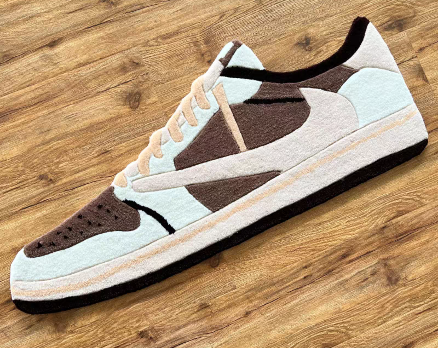 Hypebeast Travis Scott Jordan 1 Low Mocha sneaker rug laying on floor. Nike Air Jordan 1 OG SP Cactus Jack brown nubuck tufted carpet in sneaker room. Handmade sneakerhead room decor on wooden floor.