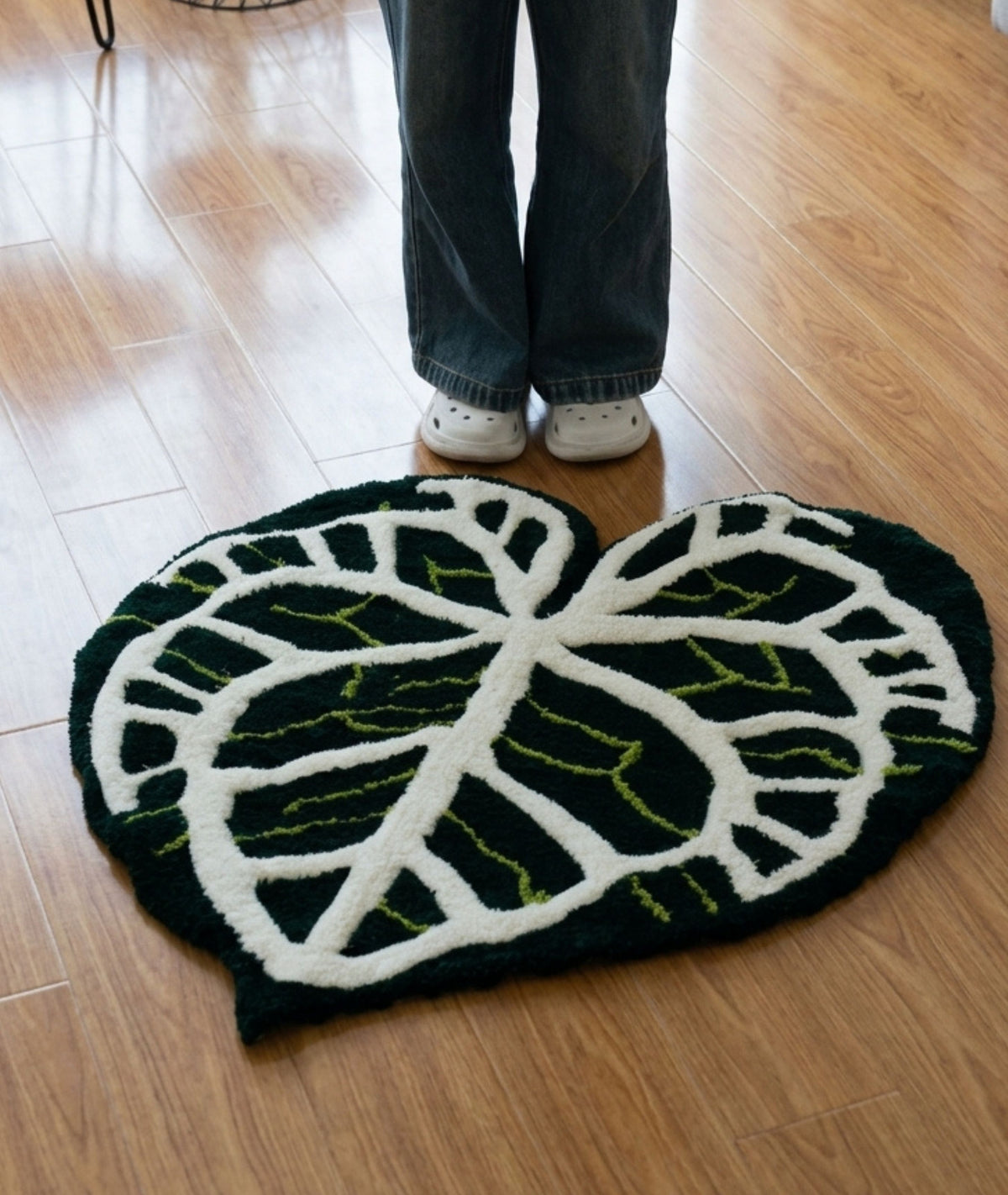 Dark green leaf rug on a wood floor beside a person, shaped botanical bedroom decor