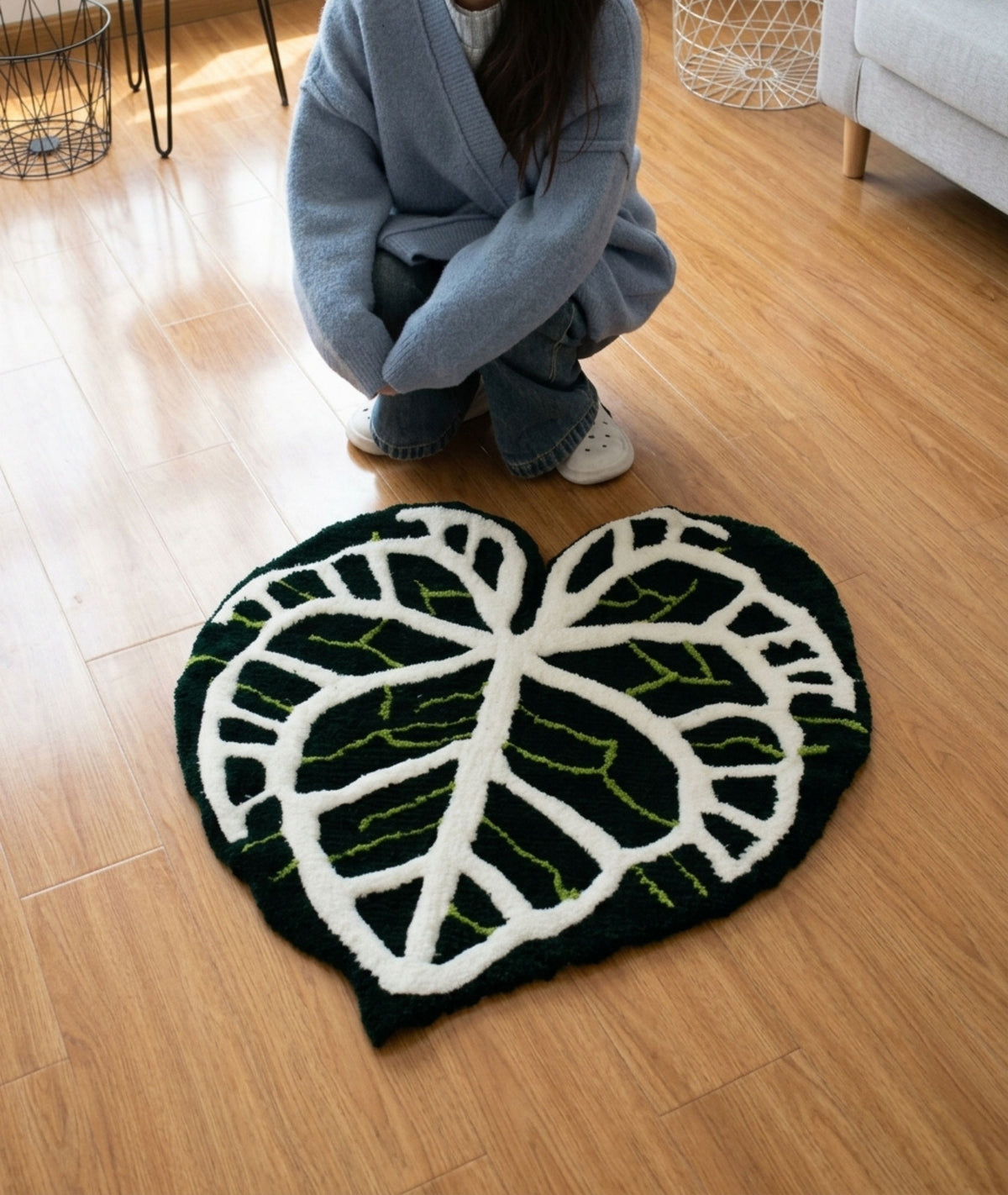 Monstera leaf rug in black and white on a wood floor, hand tufted plant room decor, top view