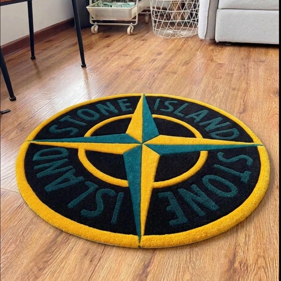 A round Stone Island branded rug on a wooden floor, featuring a compass rose design in green and yellow on a black background.