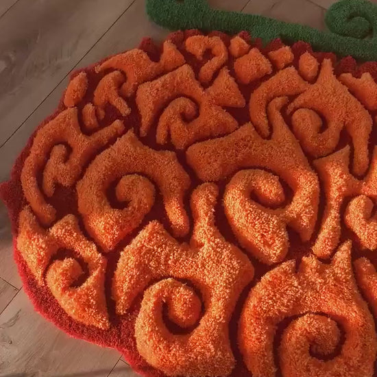 Orange swirl fruit rug video, soft acrylic tufted pile with green stem, close up floor view