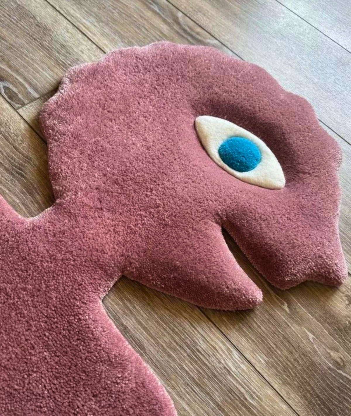 Close up of the pink rug head, raised cream and blue eye over soft tufted pile, texture detail