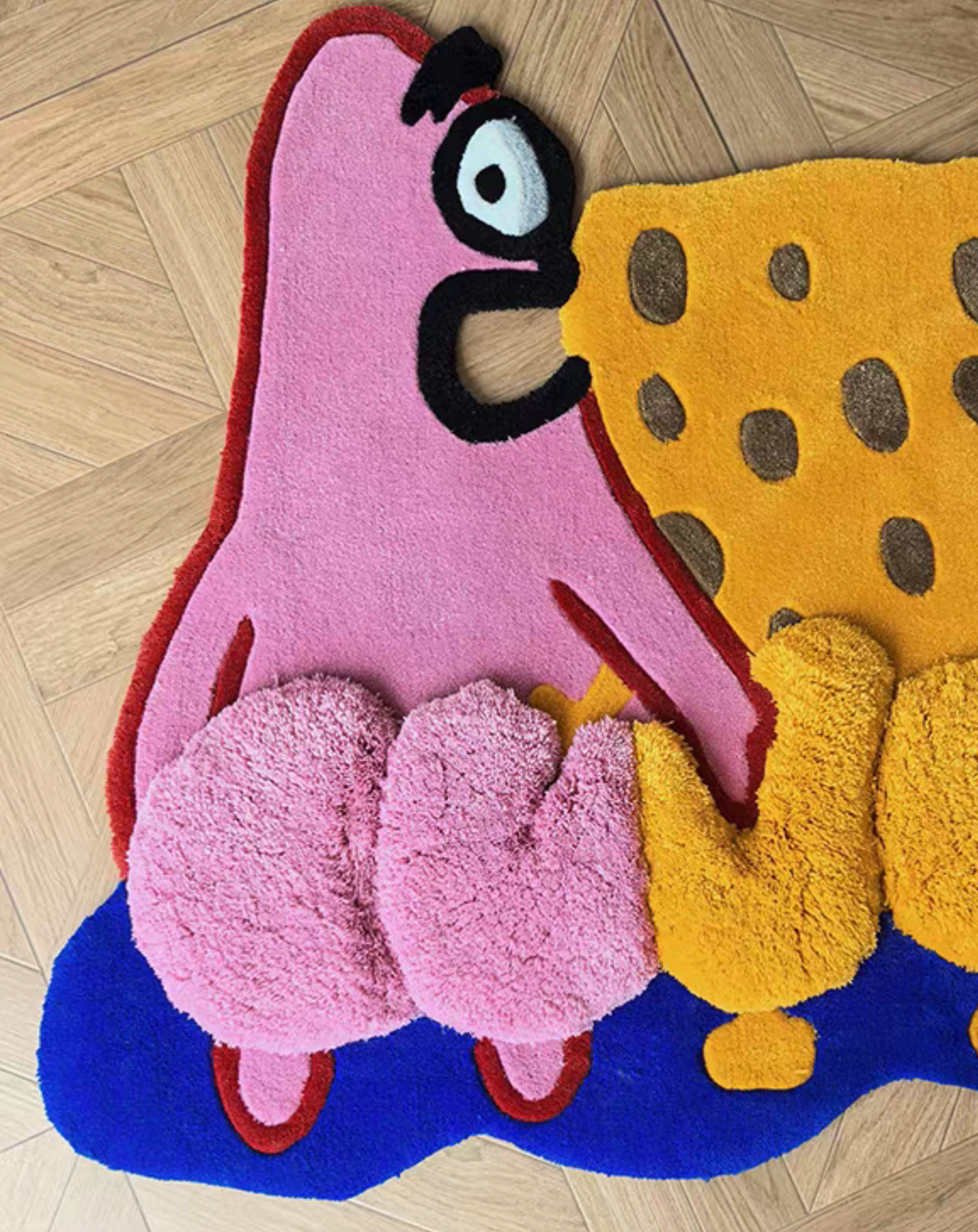 A colorful, plush, hand-tufted rug shaped like Patrick Star and SpongeBob SquarePants, displayed on a light-colored wooden parquet floor.