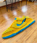 Yellow sneaker rug on a wood floor, hand tufted shoe shaped streetwear room decor, full side view