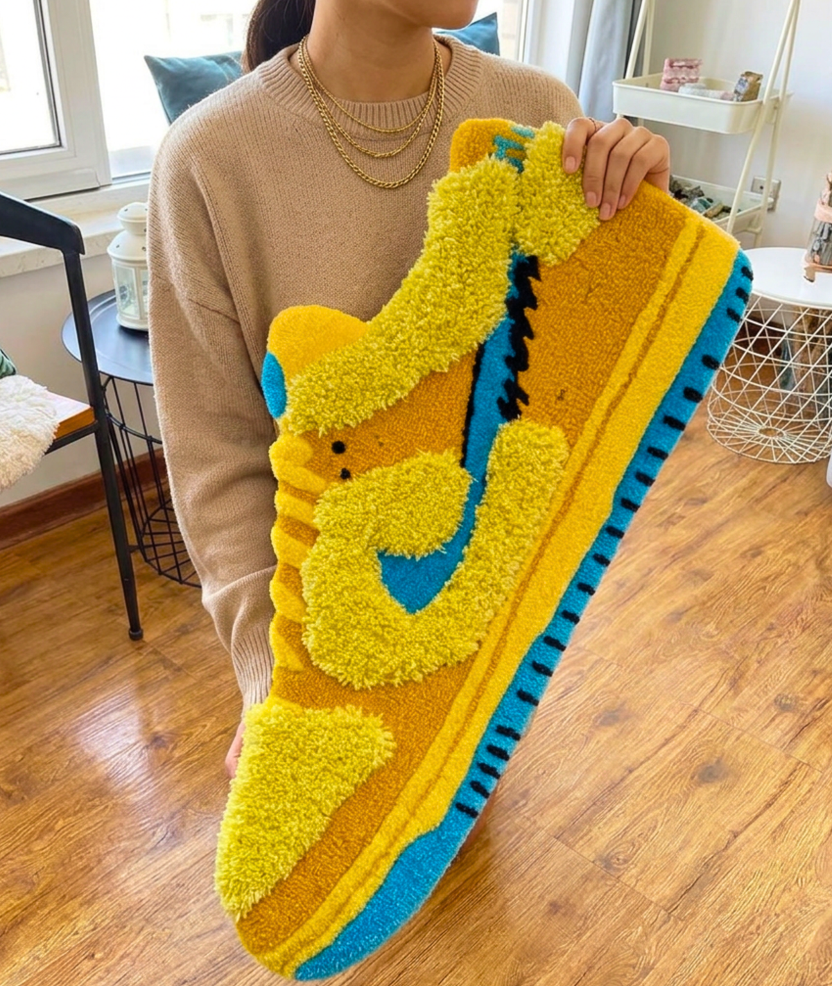 Person holding a large shoe shaped rug, fuzzy yellow and blue acrylic pile, size scale view